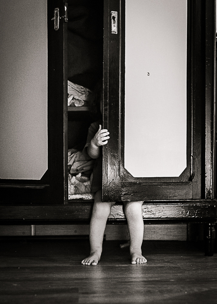 bebe se esconde en un armario, sobresalen sus pies y mano, en su casa en Pla de l'Estany, Catalunya, españa. 