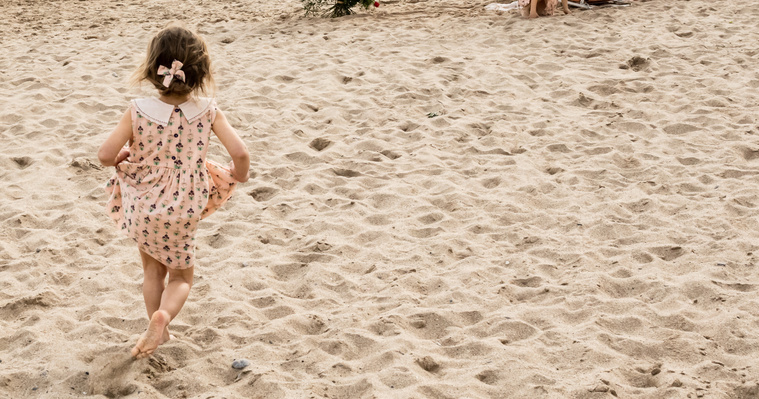 Niña corriendo descalza en la playa de les casetas del Garraf en cataluña, españa