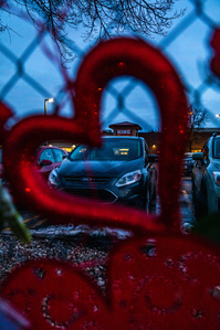 Plastic heart left by those mourning recent events hangs on fence with clear view of King Soopers sign in Boulder, CO. (Io Hartman&amp;amp;#x2F;CU Independent)