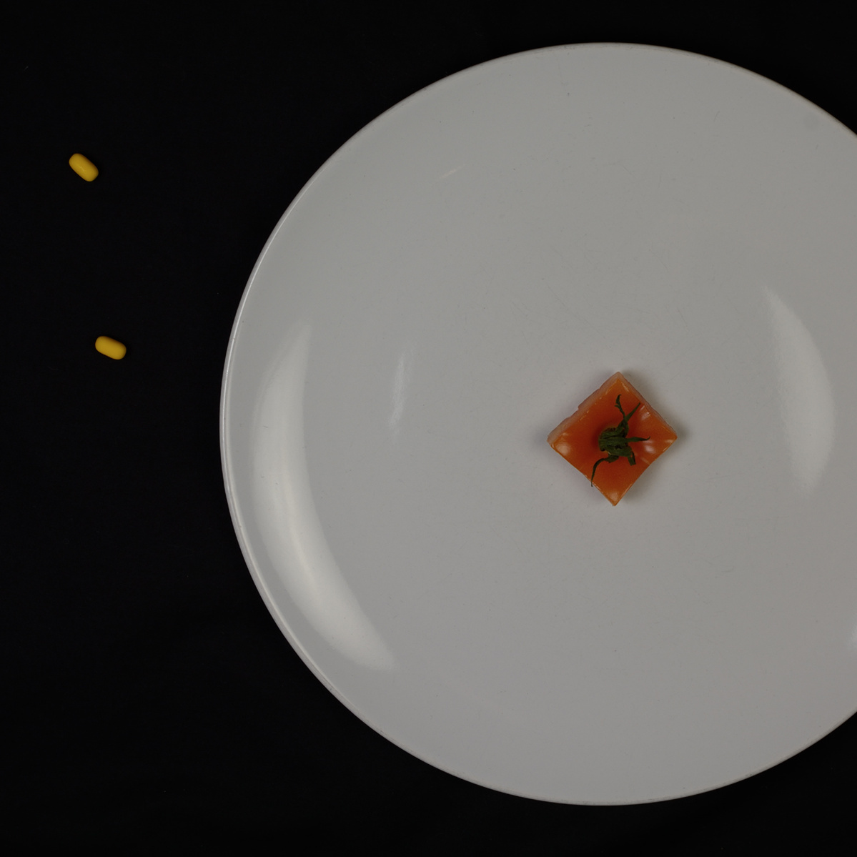 colour photograph of plate with tomato and yellow tic tacs