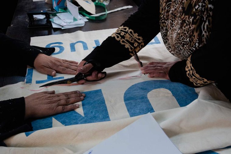 Refugee women workers in Za’atari camp measure and cut UNHCR tents into sizable pieces to be sewn into reusable tote bags for Oxfam’s Lel-Haya project. 
