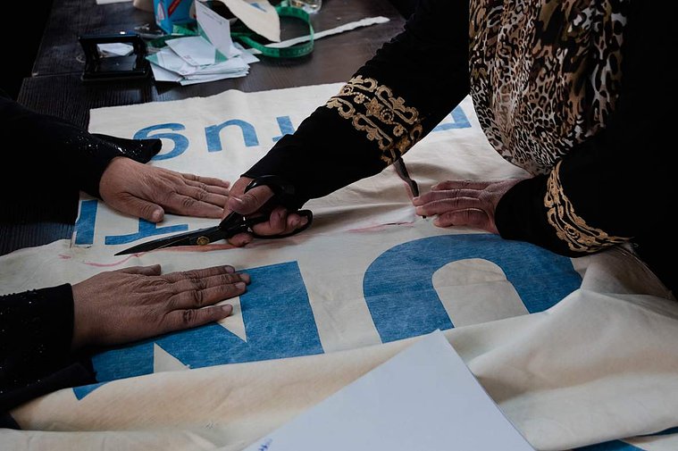 Refugee women workers in Za’atari camp measure and cut UNHCR tents into sizable pieces to be sewn into reusable tote bags for Oxfam’s Lel-Haya project. 
