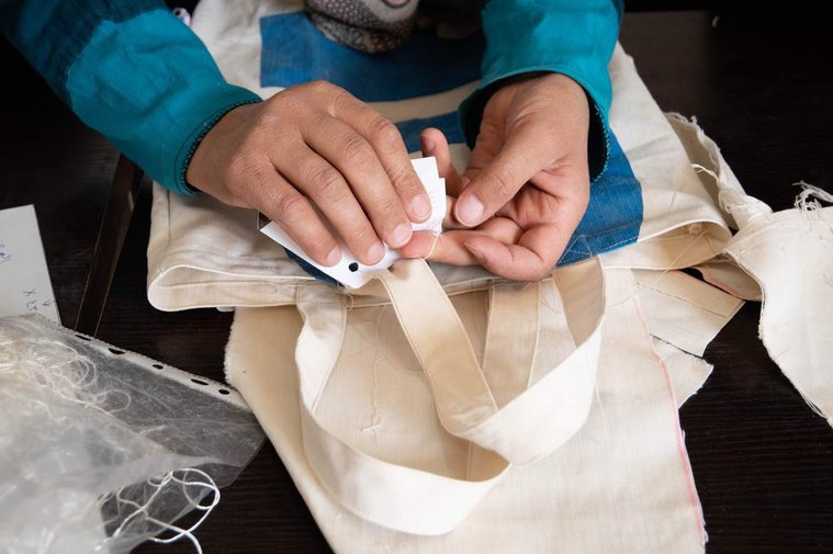 A refugee woman puts the finishing touches on handmade tote bags that will be sold through the Oxfam led Lel-Haya project in Za’atari refugee camp. 
