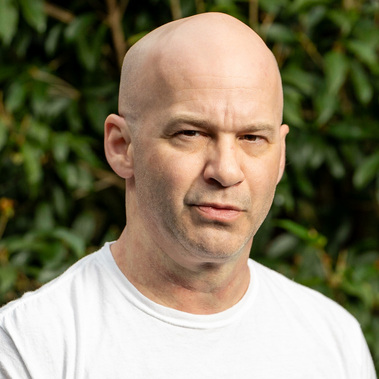 Handsome, balding male with a serious look sporting a white T-shirt. The websites author and creator of the beautiful images therein. 
