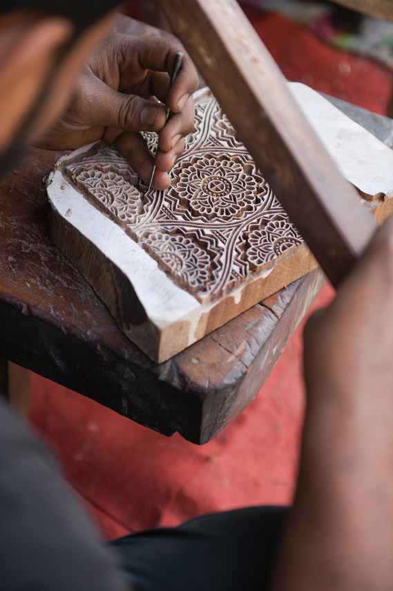 In one of the block maker studios in Bagru, India, a master artisan is immersed in the local tradition of woodblock carving. In the rustic charm of the studio, his skilled hands transform a simple piece of Sheesham into an intricate floral design. 