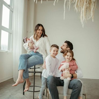 A family sits for a portrait session in the studio underneath a floral installation.