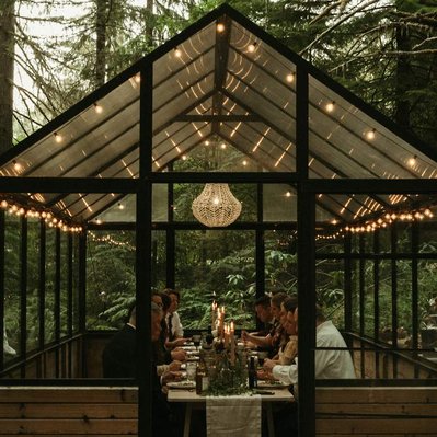 A small moody wedding in the woods with dinner served inside of a romantically lit greenhouse.