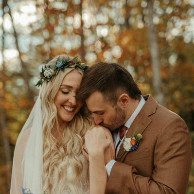 A couple snuggles under fall leaves on their wedding day up North in Lutsen MN.