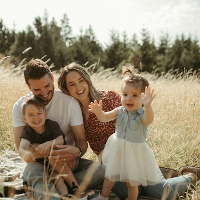 A family snuggles on a picnic blanket in a wheat field for their family photos in Oregon. 