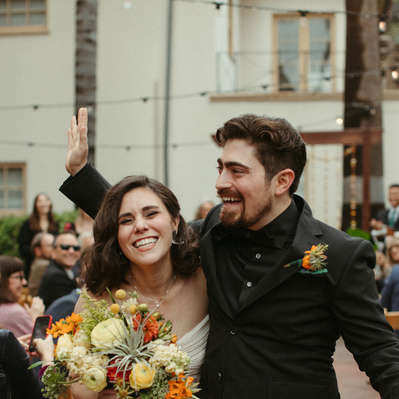 A happy couple walking down the aisle after getting married in Pasadena California with big smiles. 