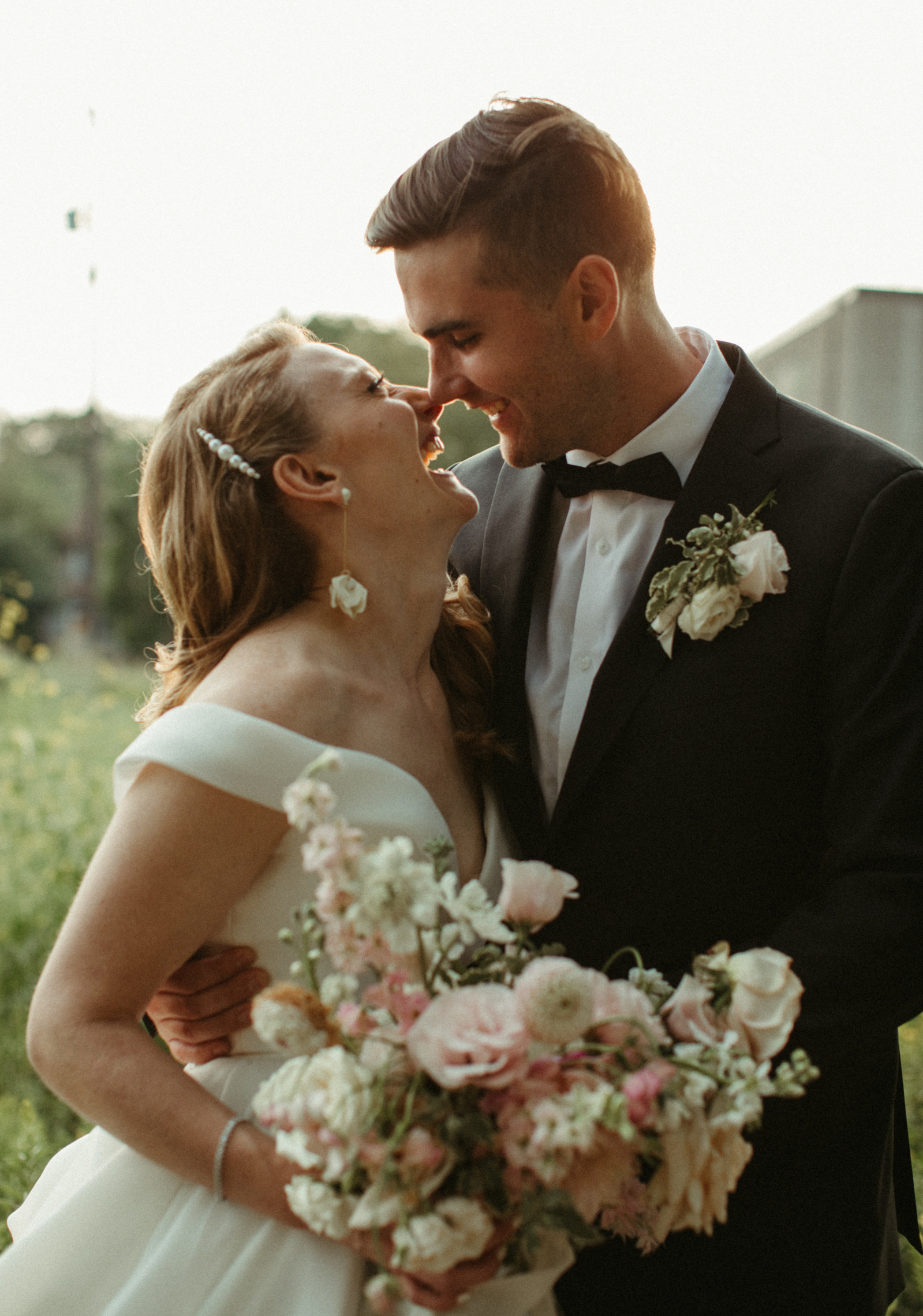 A boho couple smiles at each other on their wedding day in Minneapolis MN. Editorial style wedding with candid photos and a beautiful pink bouquet. 