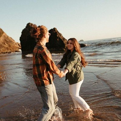 A couple twirling around and dancing on the coast as the sun sets for their engagement photos in Oregon.