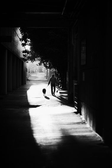 Black and white street photograph with heavy shadows and a cut of unique light.