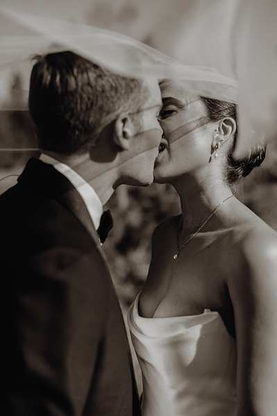 Bride and groom kissing under her veil 