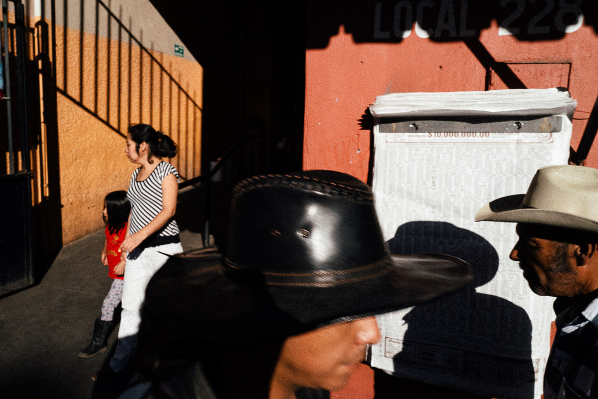 Two men in cowboy hats and a woman and child exiting a market in Oaxaca, Mexico