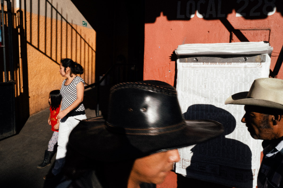 Two men in cowboy hats and a woman and child exiting a market in Oaxaca, Mexico