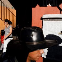 Two men in cowboy hats and a woman and child exiting a market in Oaxaca, Mexico