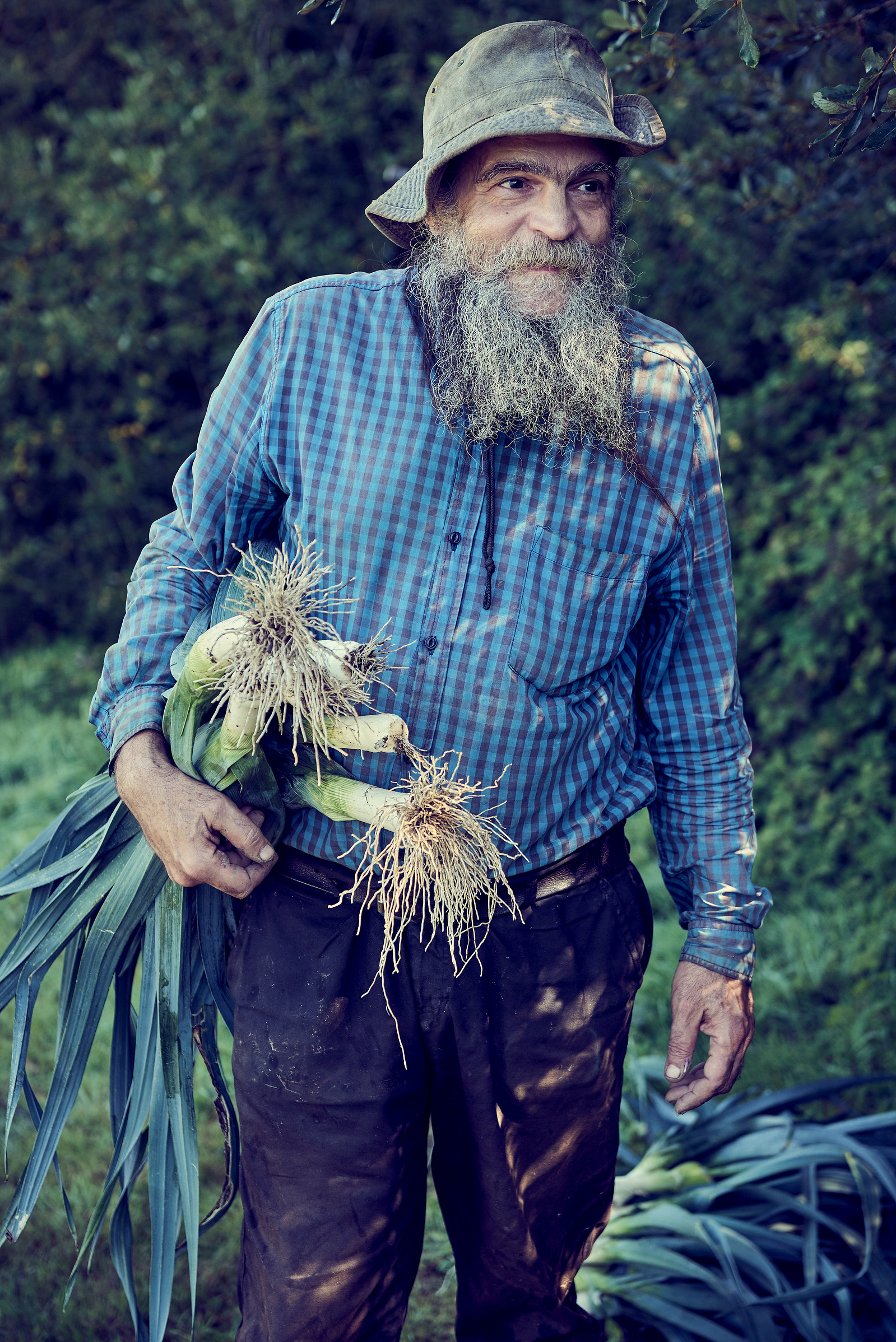 Characterful bearded man in a blue check shirt carrying leeks.
