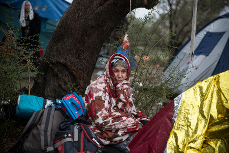 An Afghan woman uses a blanket to try to keep warm during a rainstorm at Moria transit center in Lesbos, where some waited for days to register with Greek authorities. 