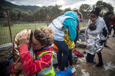 European volunteers attend to immigrants who just landed on the island of Lesbos, providing them with emergency blankets and transportation to the nearest camp.