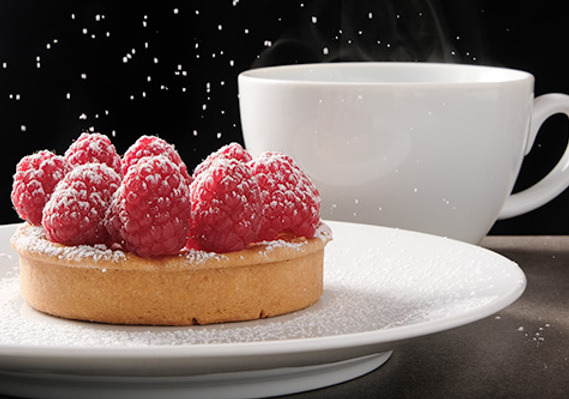 Branding image shot for a local cafe in Poulsbo, on location with studio lighting. Raspberry tart with falling sugar, and a steaming cup of coffee. Great example of food photography suitable for inclusion in a menu.