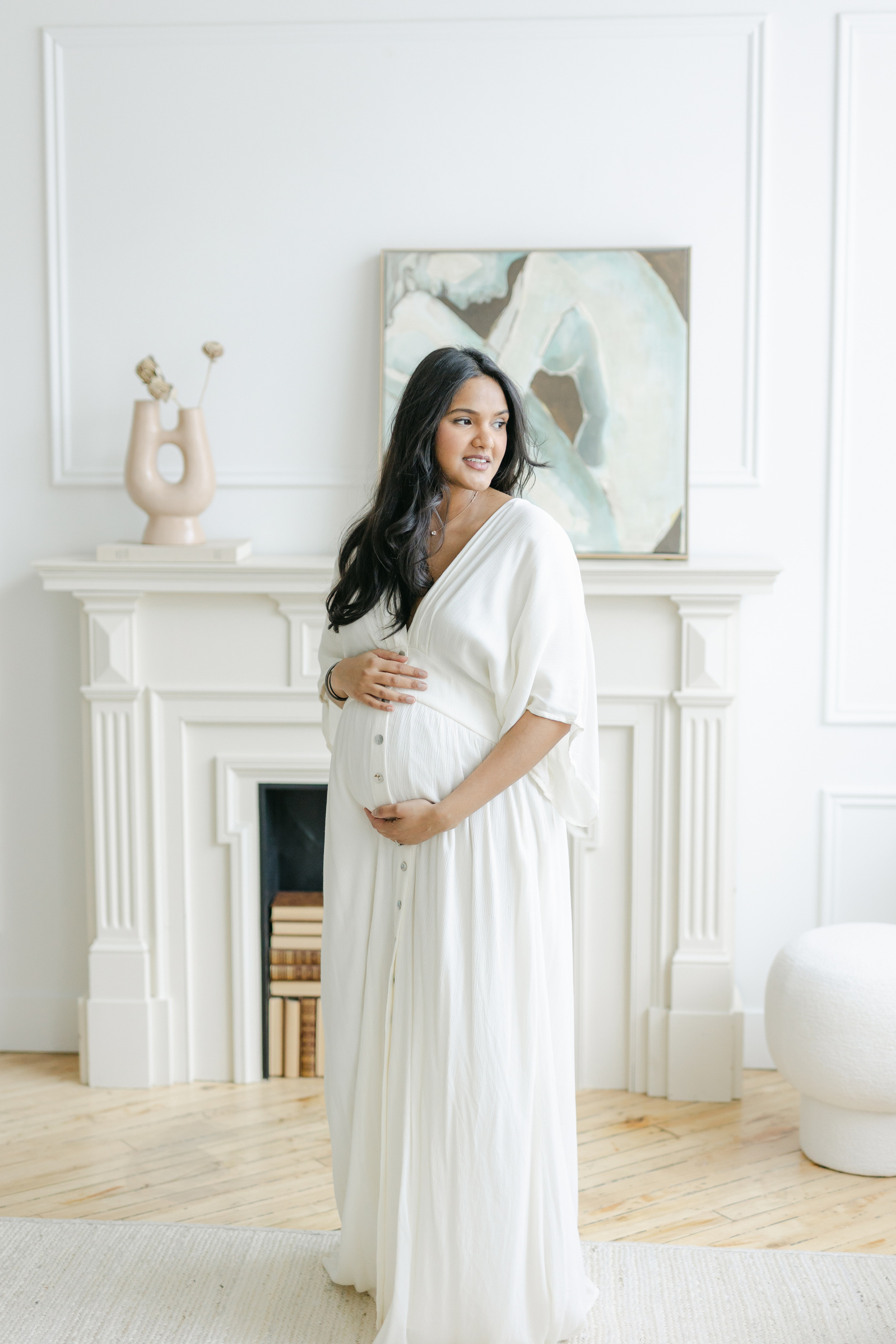 Pregnant woman holding belly in a white maternity dress