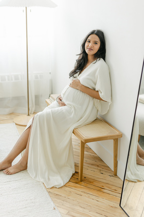 Pregnant woman sitting on the bench holding her belly