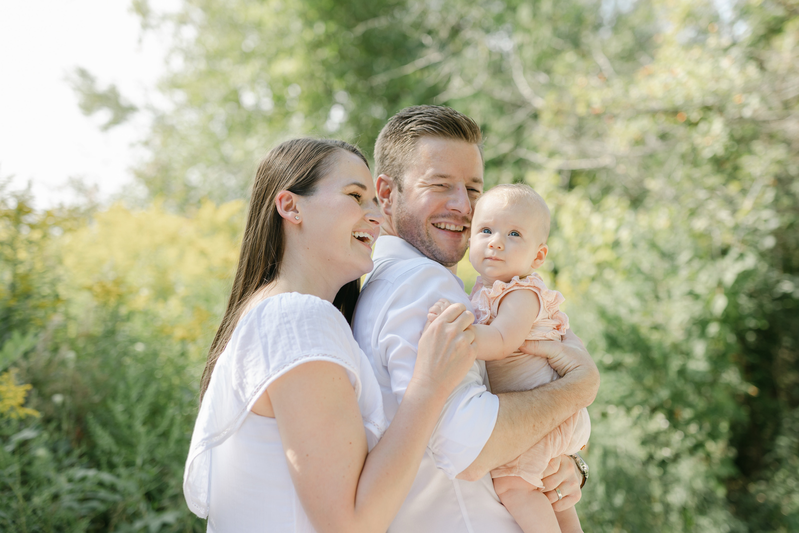 Mom and dad holding baby in a park in Toronto