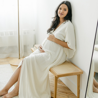 Pregnant woman sitting on a bench and holding her belly