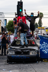 ​Protesters take command of a charred LAPD patrol car. The police declared the protest an unlawful gathering a few minutes later.