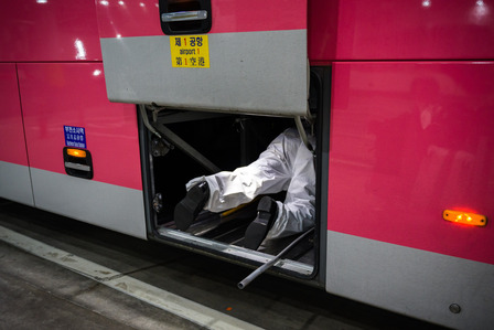 A bus driver in coveralls prepares cargo space for my luggage Friday, Nov. 13, 2020. My transportation options were limited to a network of preapproved quarantine buses that takes incoming travelers to a coronavirus testing site before heading to their de