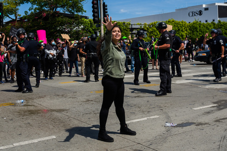 A woman begs protesters to stop throwing objects at the police, fearing the protest will turn more violent.