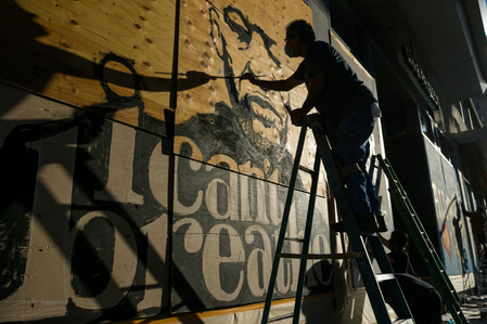 Christopher Perez, a local artist, paints a mural of George Floyd on the plywood of a boarded-up store on Hollywood Boulevard and Highland Avenue Saturday, June 13, 2020.