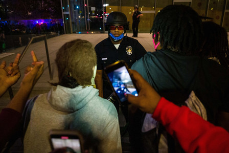 Los Angeles Police Officer Michael Silva guards the entrance to the Los Angeles Police Department headquarters as people protesting a grand jury decision to not press charges against officers who killed Breonna Taylor hurl racial slurs at Silva, Wednesday