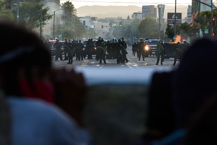 Two Black protesters shelter behind a mattress as LAPD officers fire rubber bullets at them on Beverly Boulevard.