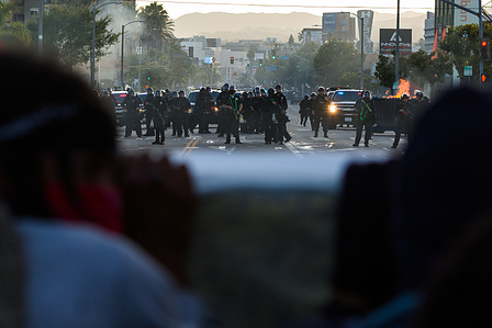 Two Black protesters shelter behind a mattress as LAPD officers fire rubber bullets at them on Beverly Boulevard.