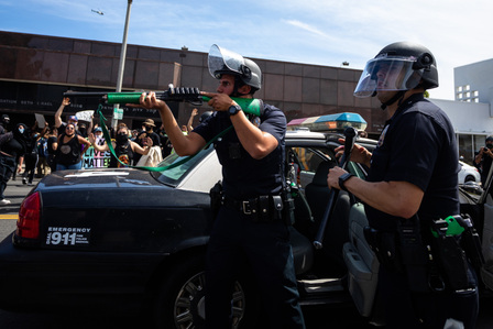 ​Los Angeles police officer Joshua Moses, center, threatens protesters with his shotgun. He did not shoot; instead, he got back into the patrol car, which sped away from the protesters.