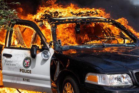 A ravaged Los Angeles Police Department patrol car burns on the intersection of Beverly Boulevard and Edinburgh Avenue. Protesters lit at least two police cars on fire during the protest in the Fairfax District.