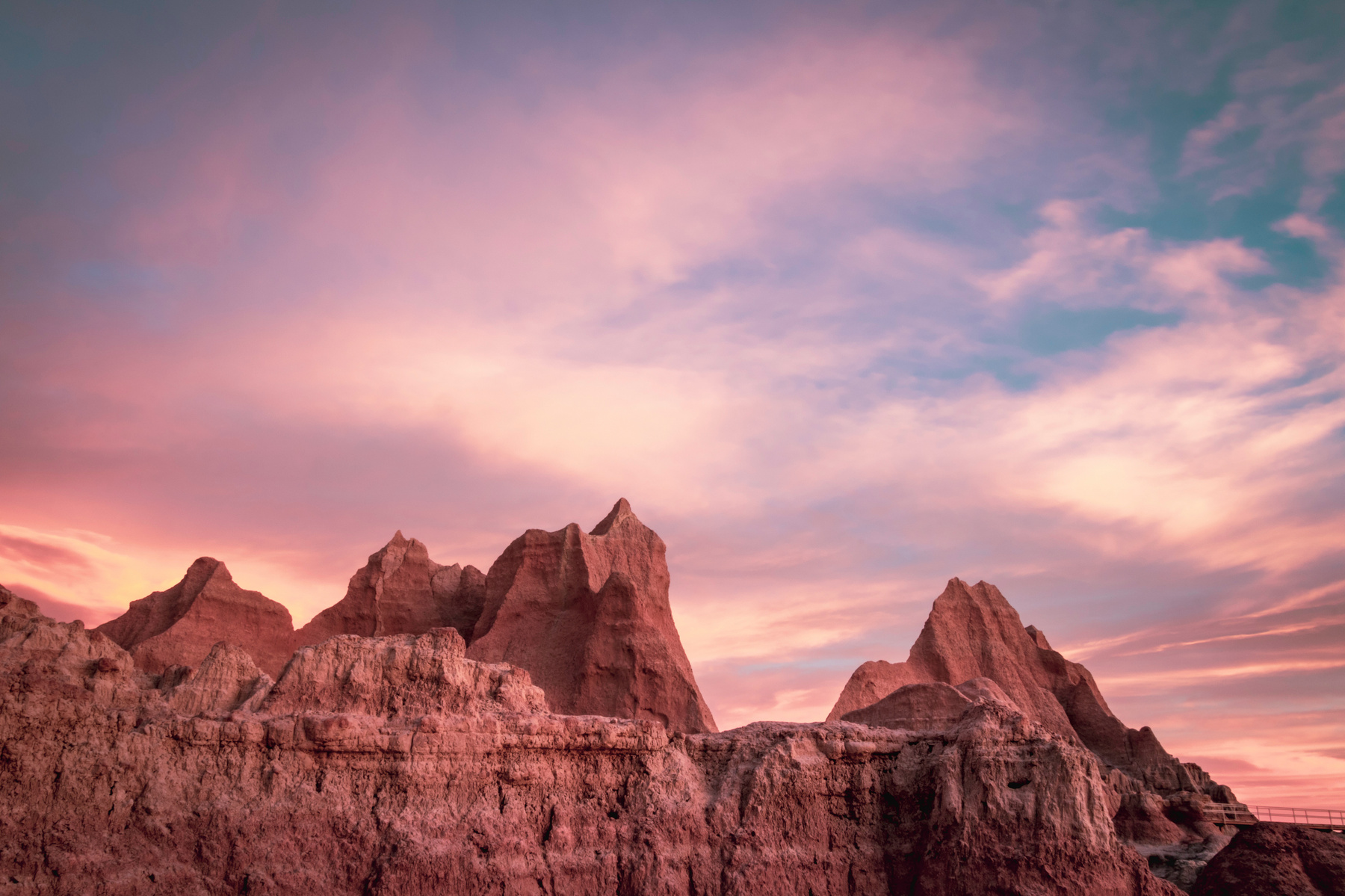 Beautiful winter sunrise at Badlands National Park in South Dakota with pink pastel clouds above the rock formations.