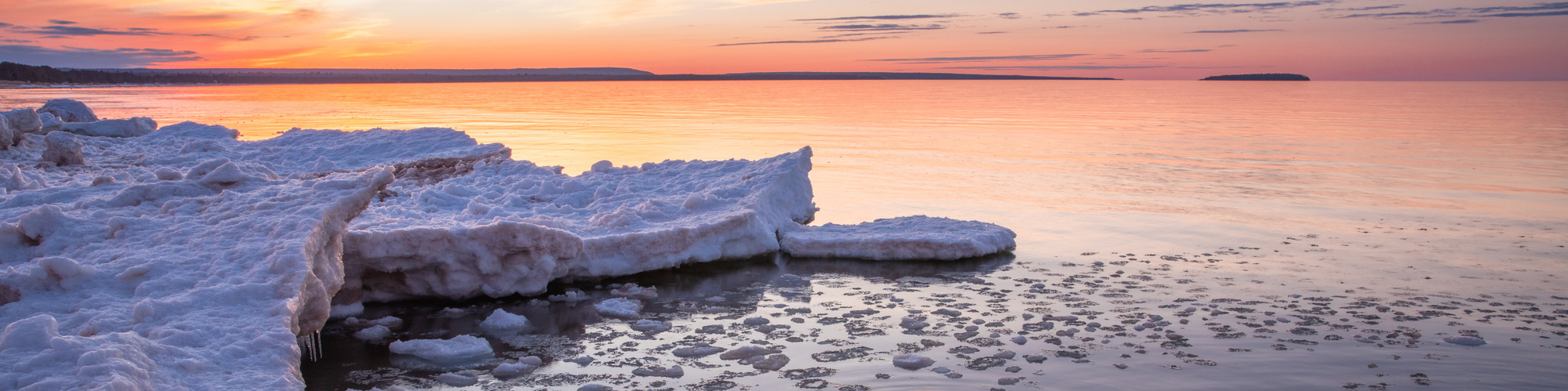 Colorful winter sunset over Lake Superior with ice shelf along the shoreline in the Upper Peninsula of Michigan