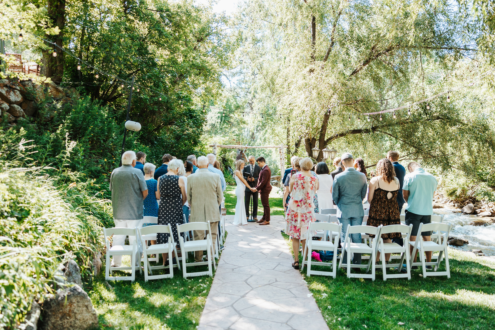 Wedding ceremony at Wedgewood Weddings - Boulder Creek by the river during an early morning ceremony in August, captured by Denver Wedding Photographer
