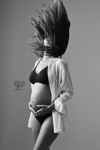 Mujer embarazada subiendo la cabeza con el pelo al viento. Fotografía profesional blanco y negro