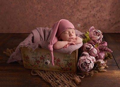 Bebe tumbado sobre un cajon decorado con flores. fotografía profesional
