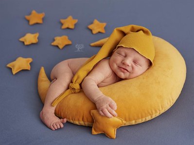Bebe tumbado sobre una almohada con forma de luna