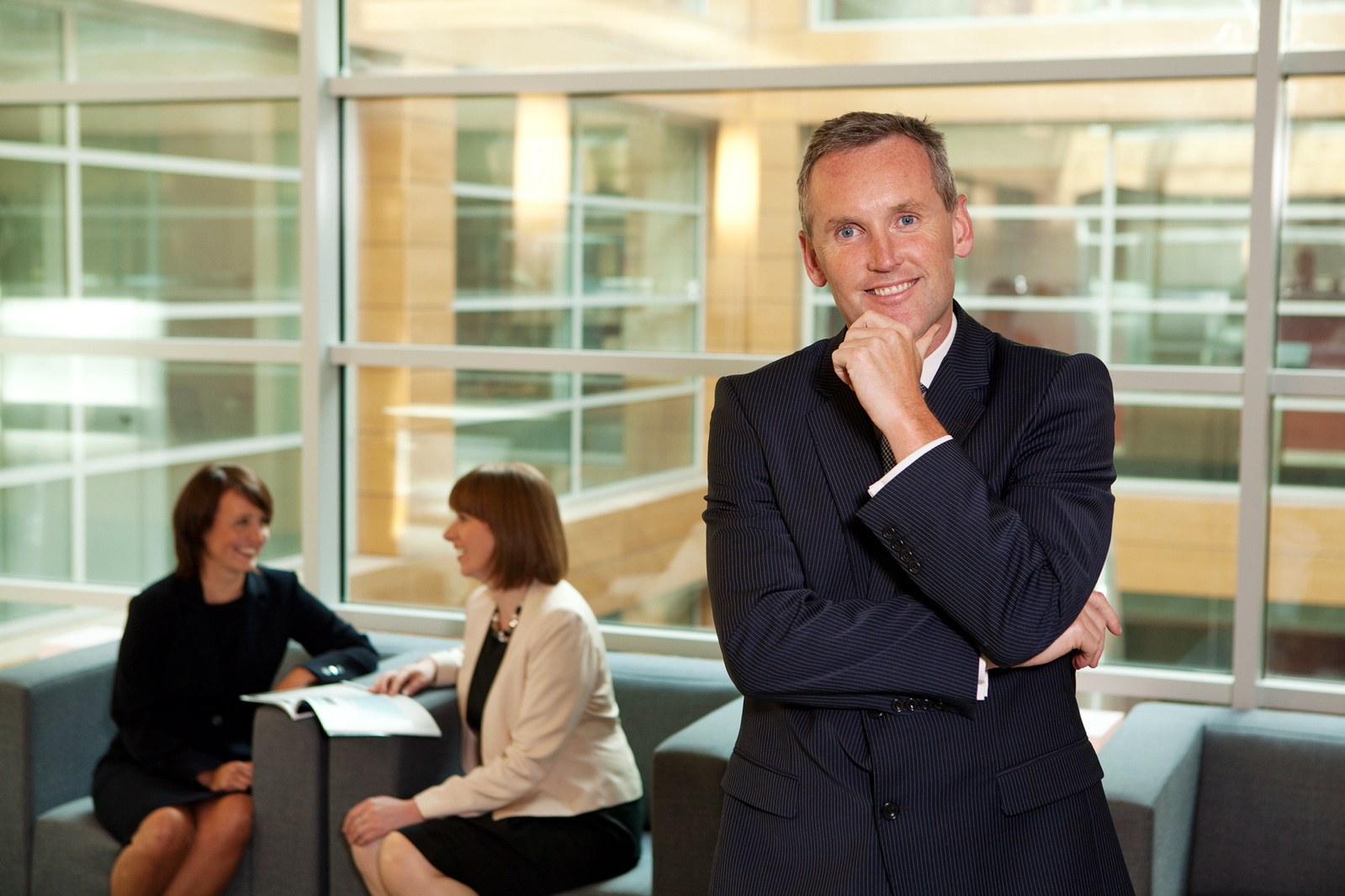 Professional business portrait of company director smiling with corporate meeting in office background