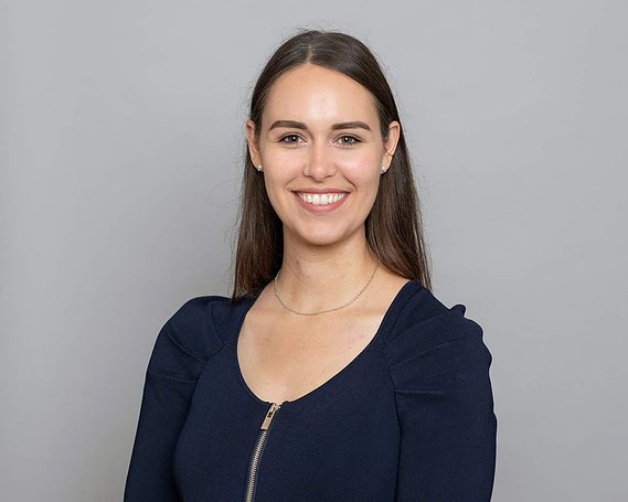 Professional business Headshot of  young female in black top grey photography studio background