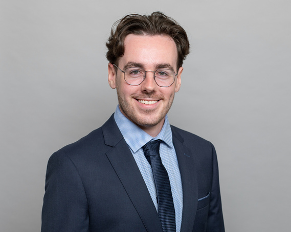 Professional business Headshot of  young male wearing glasses and business suit grey photography studio background
