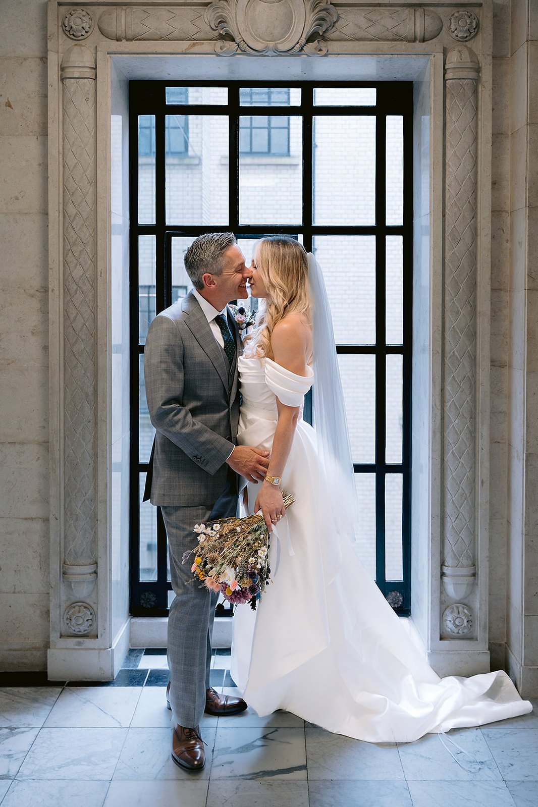 The Old Marylebone Town Hall Wedding Ruth Buscombe and Nathan Divey kissing in front of window