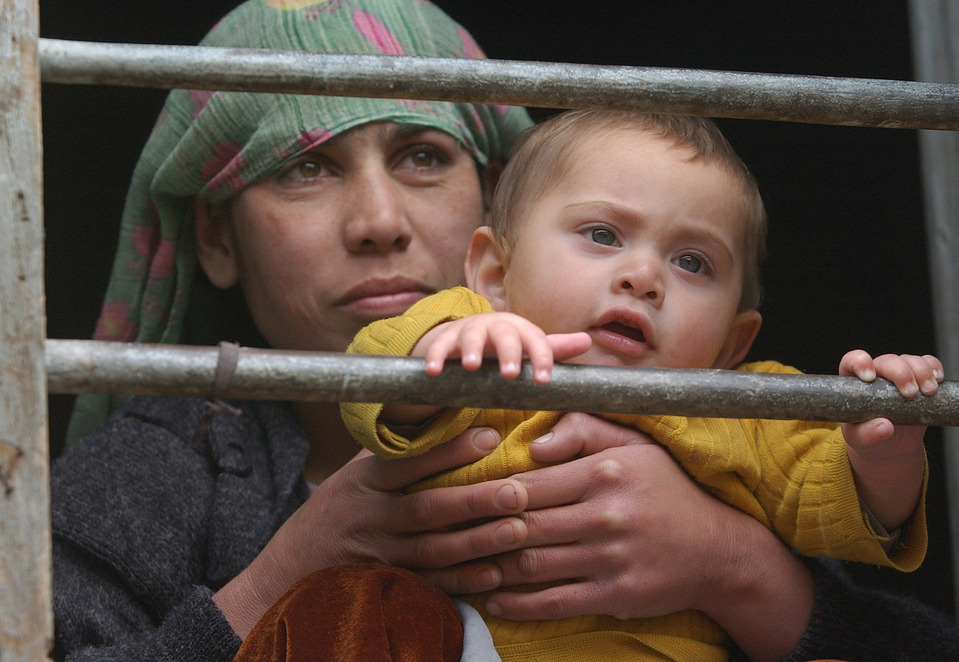 a woman in a headdress with her infant son behind prison bars