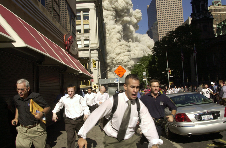 a group of men running to escape the blast of 9/11